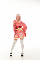 Wall Mural - full length of woman in blonde wig and pink kimono pointing at camera on white, cosplay culture