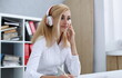 © H_Ko - Beautiful female student with headphones listening to music and learning. Hold the pen in his hand and looking at laptop monitor