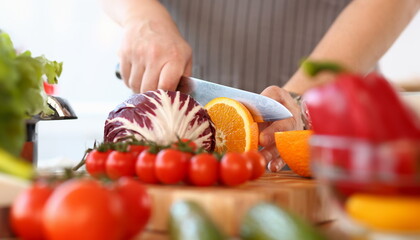 Wall Mural - Knife Chopping Juicy Orange Fruit Photography. Cabbage and Red Tomato for Vegan Food. Chef Cut Fresh Vegetable Salad. Vegetarian Recipe Blog. Cooking Healthy Meal with Citrus Partial View Shot