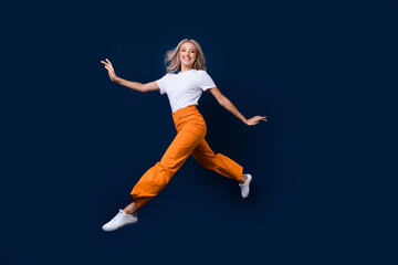 Wall Mural - Full length photo of adorable pretty girl jumping going moving empty space isolated on dark blue color background