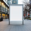 Vertical blank white billboard at bus stop on city street. In the background buildings and road. Mock up.