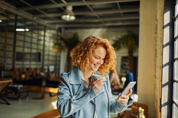 Wall Mural - Young business woman using smartphone on coffee break in modern workspace