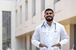 Portrait of a Latin American male doctor, nurse, veterinarian standing outside the clinic on the street in a white coat and smiling and confidently looking at the camera