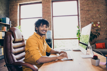 Photo portrait of handsome young guy wear yellow shirt cheerful remote working workplace sit table stylish room interior home office design