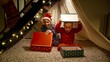 Two cheerful boys in pajamas playing in tepee tent under stairs and opening Christmas gifts and presents from Santa. Winter holidays, celebrations and party.