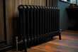 black metal heating radiator installed near the wooden wall inside the room.Modern radiator in the central heating system.House heating