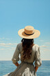 © goami - back view of woman in summer sun hat standing by sea or ocean water an looking at nature, follow me concept