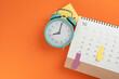 close up of calendar and alarm clock on the orange table background, planning for business meeting or travel planning concept