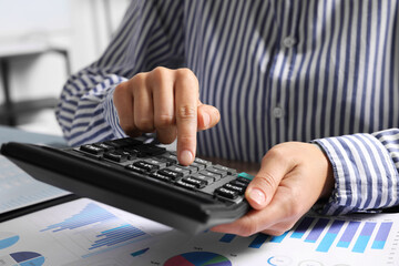 Poster - Woman using calculator at table indoors, closeup