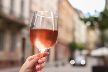 Wall Mural - Woman holding glass of rose wine outdoors, closeup. Space for text