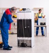 © Elnur - Two contractors repairing fridge at workshop