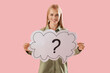 Young woman holding speech bubble with question mark on pink background