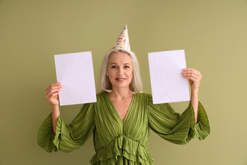 Poster - Mature woman in party hat with blank paper sheets on green background