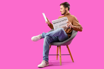 Poster - Young man with newspaper and tablet computer in armchair on purple background