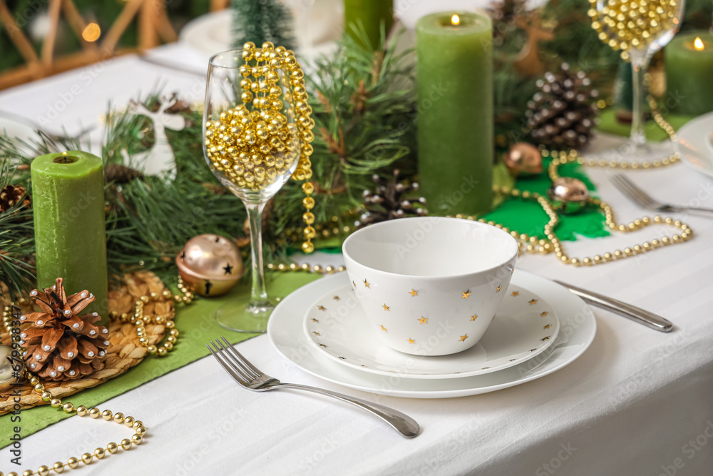 Christmas table setting with burning candles in room, closeup