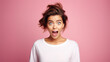 Funny surprised woman with a goofy face wearing white t-shirt isolated on pink background