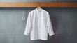 A crisp white chef's jacket hanging neatly on a stainless steel kitchen hook,