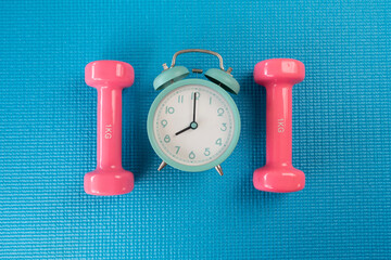 Wall Mural - Time for exercising alarm clock and dumbbell with blue yoga mat background, sport and healthy concept