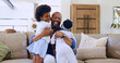 © Charlize D/peopleimages.com - Love, hug and happy black family on a sofa with care, trust and bond at home together. Smile, embrace and excited girl children in a living room with father for support, security or weekend freedom