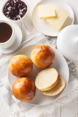 Wall Mural - Cardamom Buns served with butter, jam and coffee closeup on the wooden table. Vertical top view from above