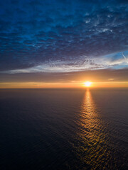 Wall Mural - A view from a drone flying over the sea early in the morning at sunrise, with the rising sun and a colorful sky