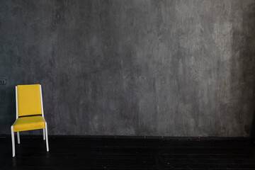 Wall Mural - yellow chair on a gray background in a dark room interior minimalism