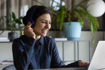 Sticker - Happy Indian female student in wireless head phones studying at laptop computer, watching learning webinar, enjoying virtual training, remote education. Employee making video conference call,