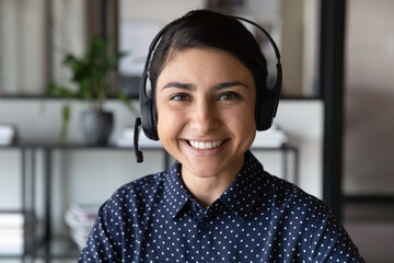 Canvas Print - Happy young female Indian call center operator, client support service employee portrait. Student, office worker woman in headphones, headset looking at camera, smiling. Video call screen head shot