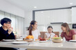 © Stella - Happy family having meal in dining room. Parents, daughter and aunt sitting around dining table and having fun during breakfast. Cheerful family mother father and kid enjoy eating food together.