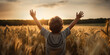 Young boy in a field, hands raised high in joy