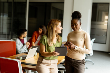 Wall Mural - Two young business women with digital tablet in the office in front of their team