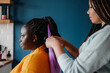 © gstockstudio - Close-up of hairdresser braiding hair to a young African woman in salon