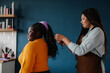 © gstockstudio - Confident African hairdresser braiding hair to a smiling female customer in hair salon