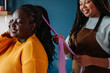 © gstockstudio - Happy African American hairdresser braiding hair to a female customer in salon