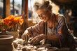  Elderly woman shape a clay vase in pottery studio.