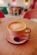 A cup of cappuccino on the table in a pink cafe