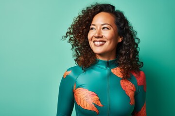 Wall Mural - Portrait of a cheerful woman in her 30s showing off a vibrant rash guard against a soft green background. AI Generation