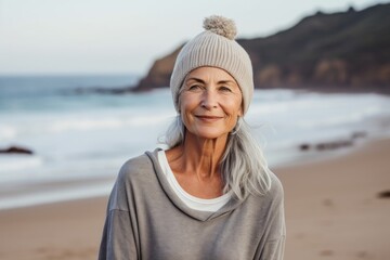 Wall Mural - Portrait of a content woman in her 60s sporting a trendy beanie against a sandy beach background. AI Generation