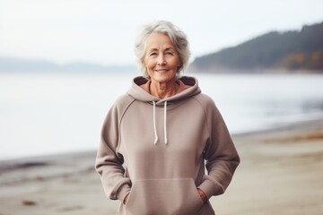 Portrait of a tender woman in her 70s sporting a comfortable hoodie against a calm bay background. AI Generation