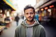 © CogniLens - Portrait of a tender man in his 30s dressed in a comfy fleece pullover against a vibrant market street background. AI Generation
