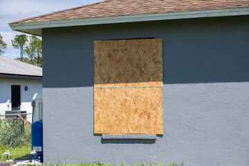 Wall Mural - Plywood mounted as storm shutters for hurricane protection of house windows. Protective measures before natural disaster in Florida