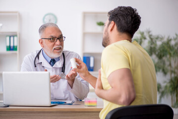 Wall Mural - Young male patient visiting old male doctor