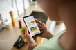 © Vorda Berge - Young woman using recipe app on smartphone for preparing meal at home