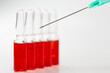© CONQUEROR - İnjection needle in selective focus. Injection ampoules of hormone B12 out of focus.