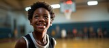 Fototapeta  - In the bustling school gym, a young African boy passionately pursues his dream of becoming a basketball star, showcasing his athletic skills and embracing a healthy lifestyle through the sport. With