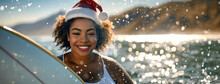 Happy African American Woman In Santa Hat With Surfboard On Tropical Beach At Sunset. Ocean Waves On The Background.