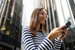 © ADDICTIVE STOCK - Young Woman Using Smartphone in Urban London Setting