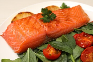 Tasty grilled salmon with basil and tomatoes on white plate, closeup