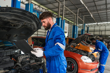 Auto mechanic in blue uniform are repair and maintenance auto engine is problems at car repair shop.