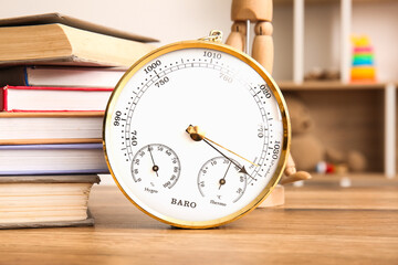 Wall Mural - Aneroid barometer and books on wooden table in room, closeup